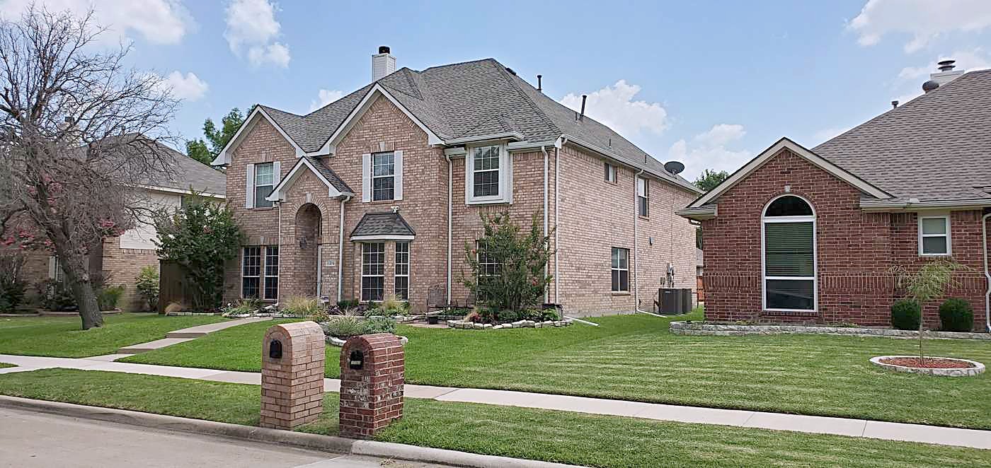 Brick homes along a North Texas street with shingle roofs and wide front lawns